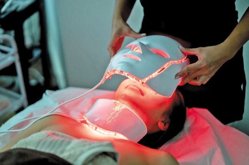 A guest receiving an LED light therapy mask treatment